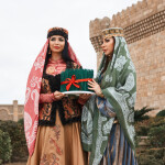 Novruz holiday in Azerbaijan. Two women in national clothes holding sprouts of spring wheat grass semeni for Novruz holiday